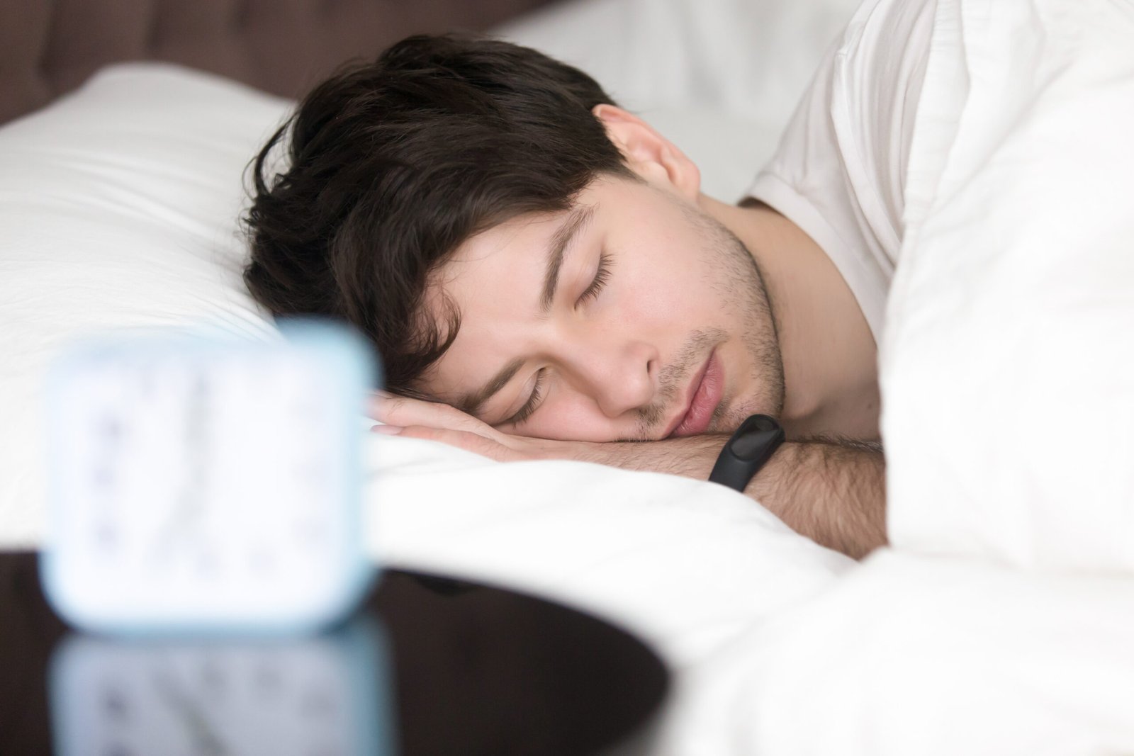 Young man sleeping peacefully while wearing a smart wristband for better sleep tracking